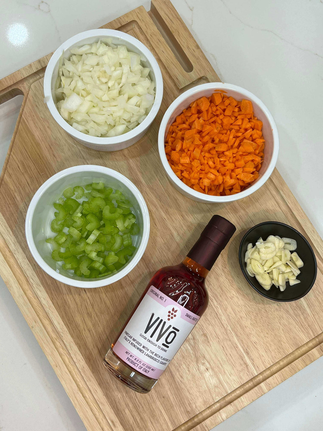Bolognese sauce prep with chopped vegetables and VIVO Lambrusco Vinegar on cutting board
