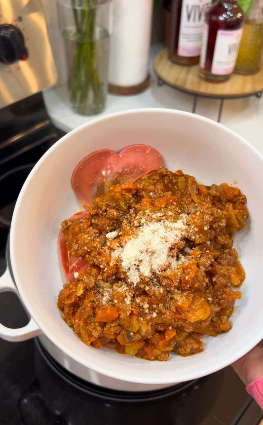 Vivo Bolognese recipe served in a white bowl with tomatoes and cheese garnish.