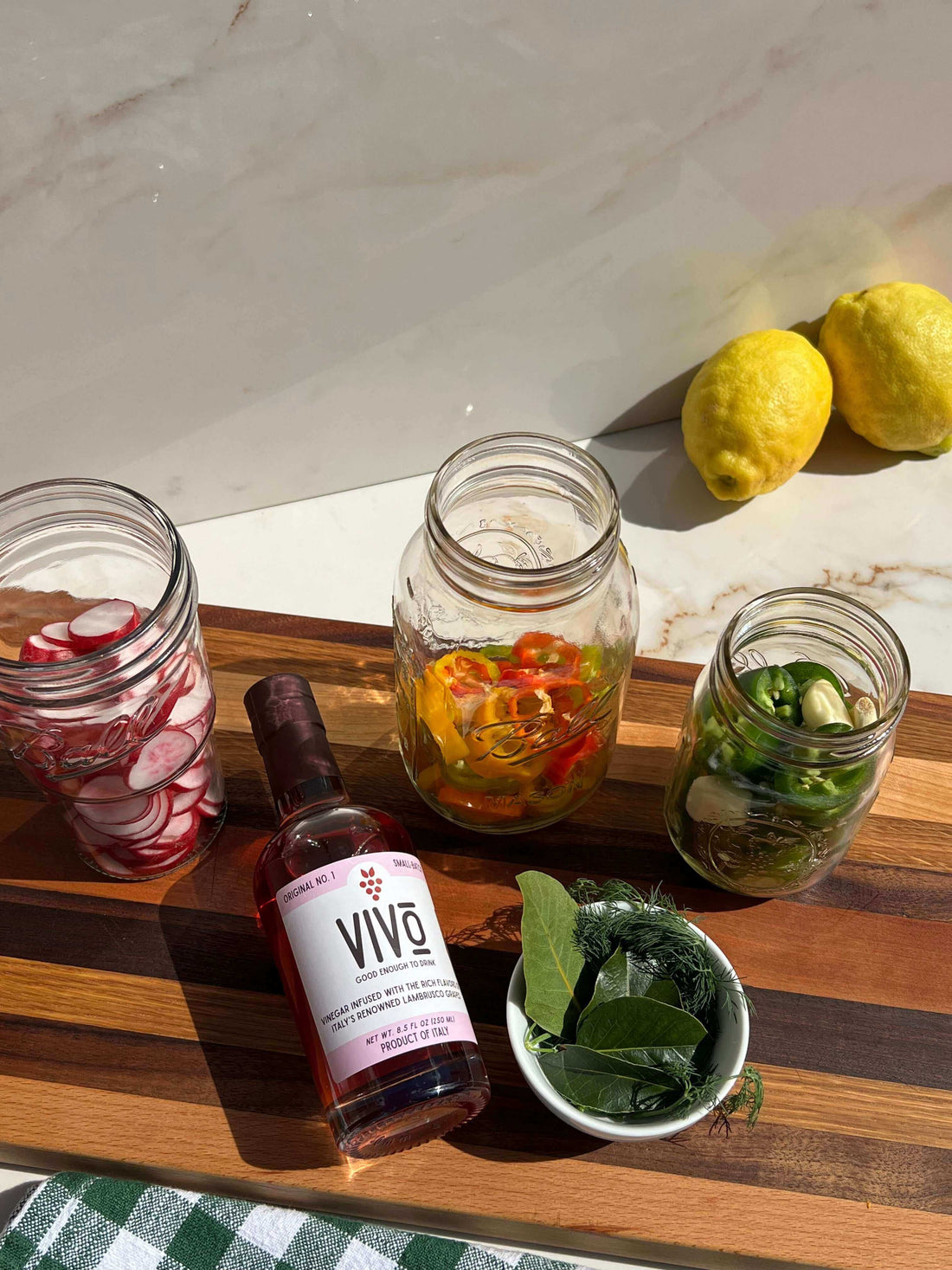 Ingredients for quick pickled vegetables including jars of vegetables and a bottle of seasoning on a wooden cutting board.