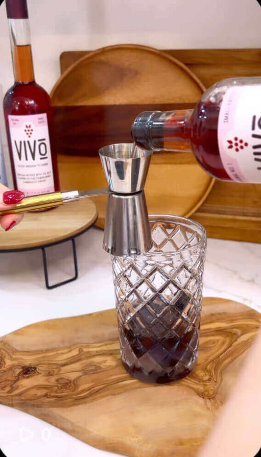 Pouring ingredients into a glass to create a Vivo blackberry smash mocktail.